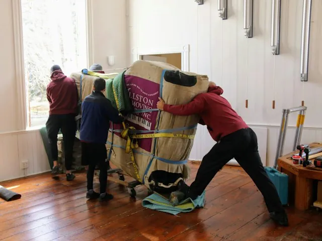 a moving crew carrying wrapped furniture